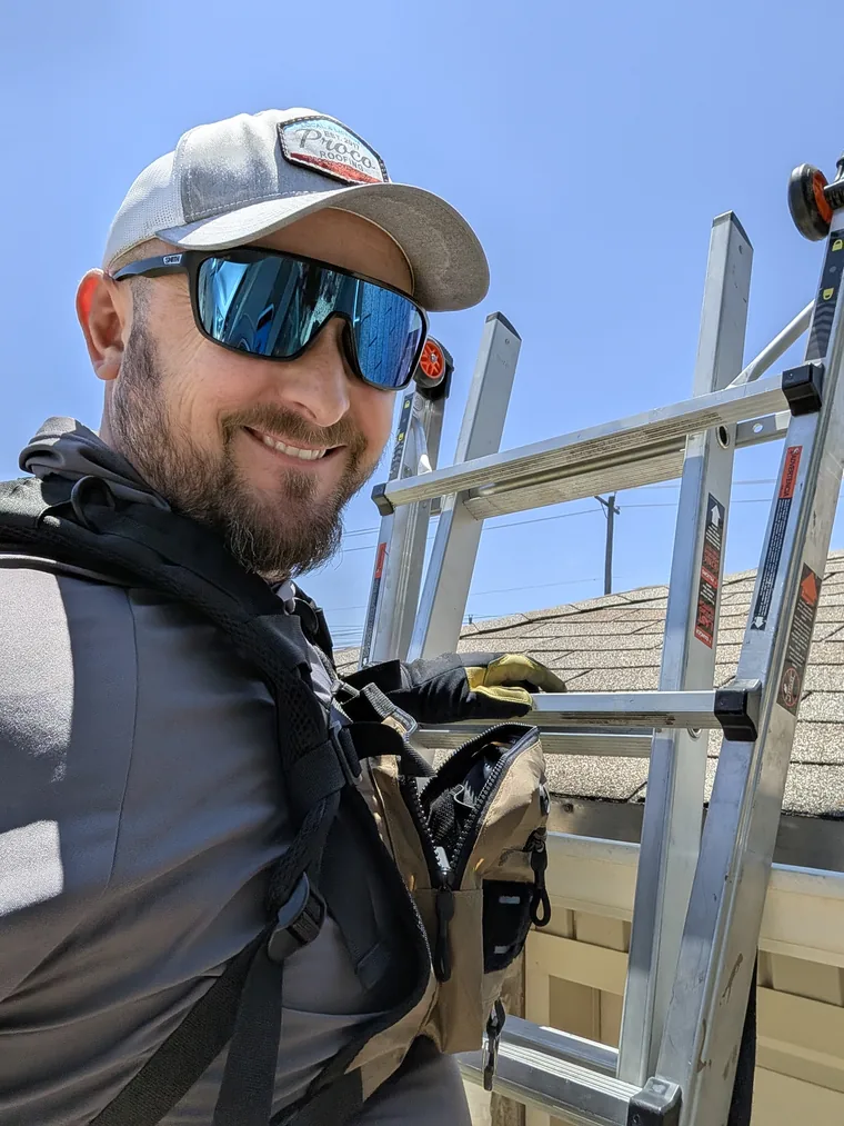 David Rodrigues documenting a roof from a ladder during a field inspection