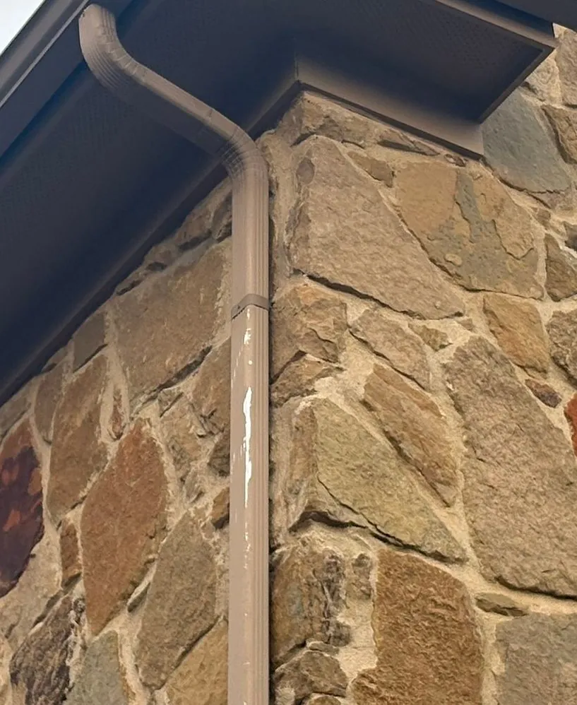 Downspout on the corner of a Central Texas home carrying water from the gutter to the ground