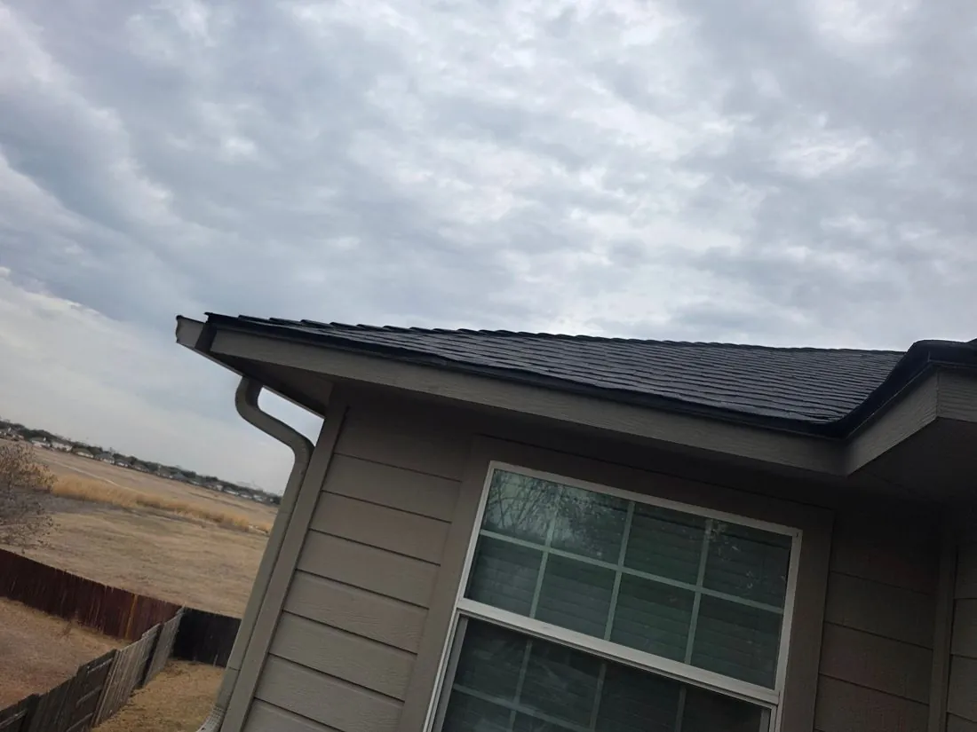 Eave line of a Central Texas roof where soffit intake is measured for ventilation sizing