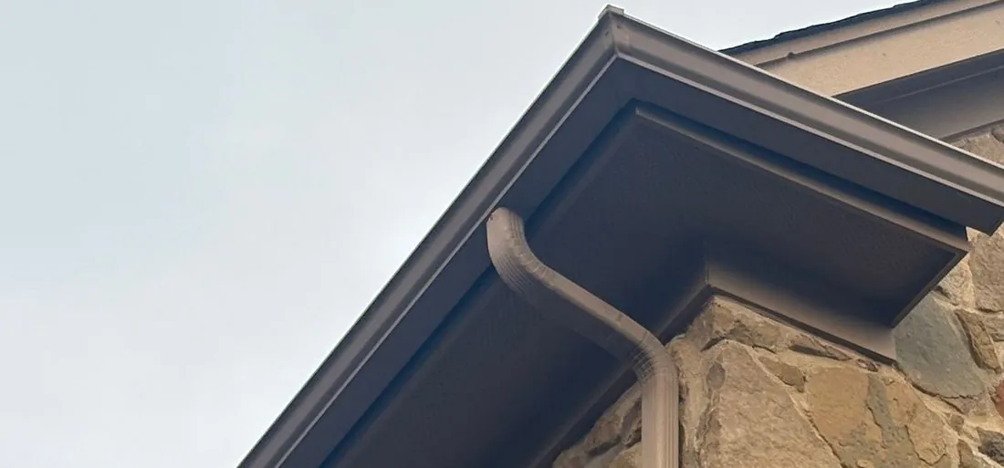Gutter mounted on the fascia of a Central Texas home with the roof edge metal reaching into it