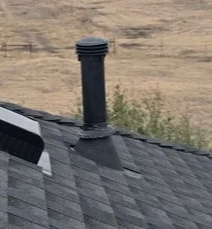 Pipe boot on a plumbing vent stack, rubber collar around the pipe and metal flange lapped with the shingles