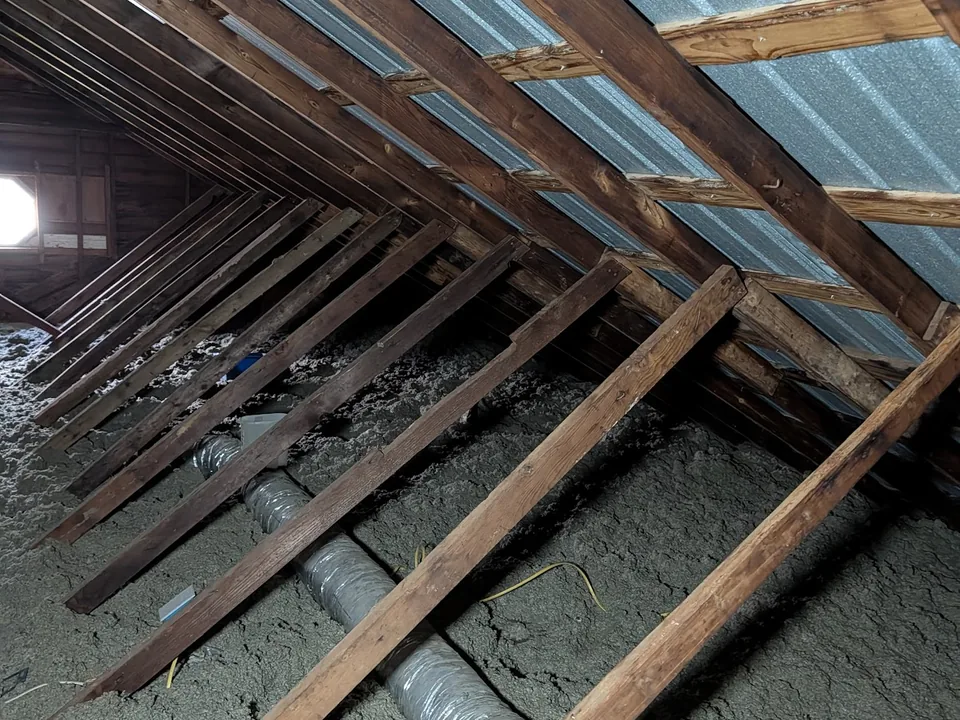 Attic view of rafters, foil-faced roof deck, ducts and blown insulation
