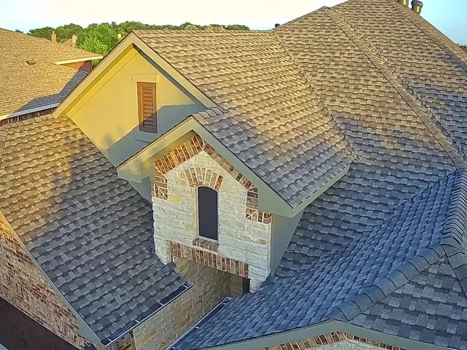 Drone view of a shingle roof showing a stone dormer and valleys