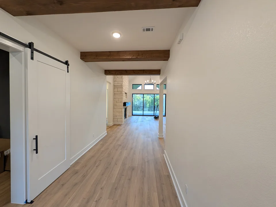 Hallway with white walls, stained wood beams and a sliding barn door