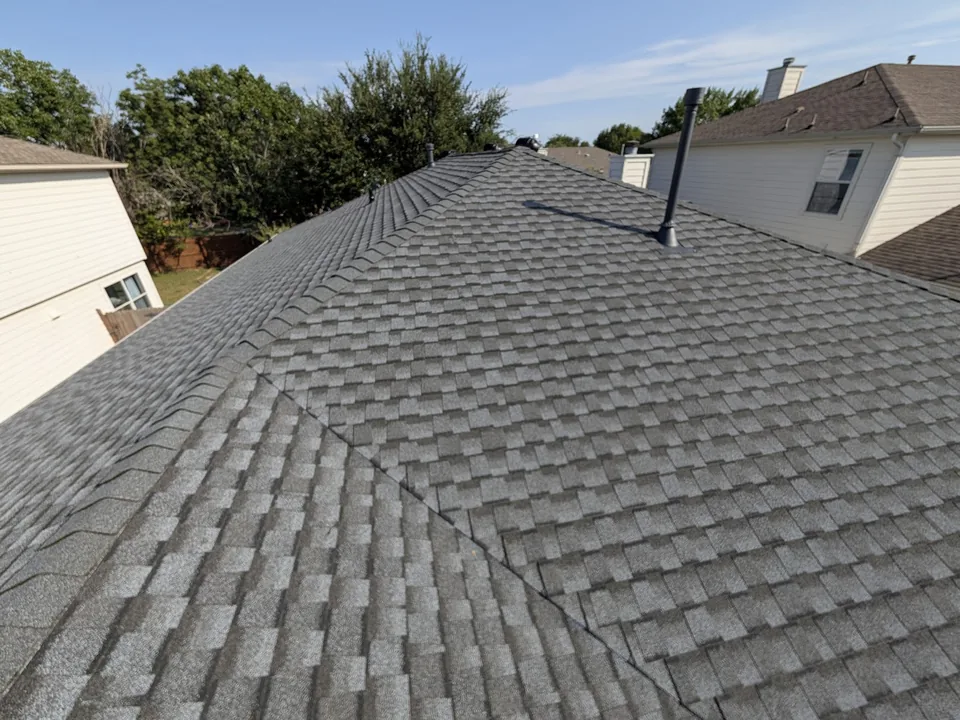 Architectural shingles meeting at a hip, with a pipe vent