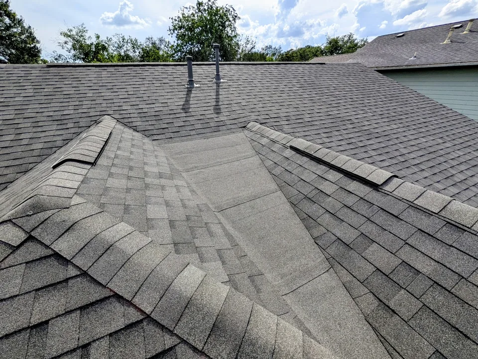 Two hips meeting a low-slope section of a shingle roof
