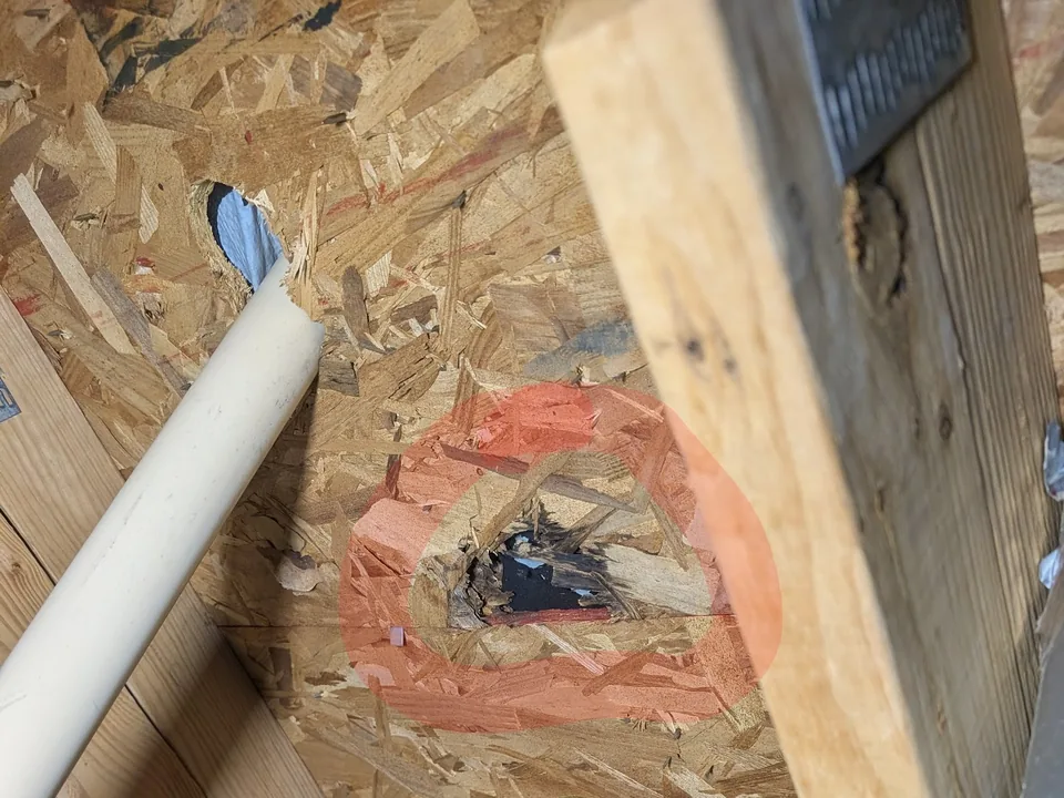 A circled hole through the roof decking, seen from the attic