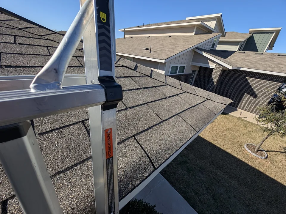 A ladder secured at the eave of a shingle roof