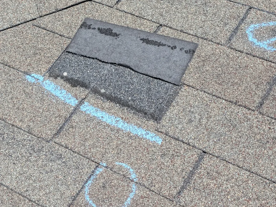 Missing shingle tab on a roof slope, marked with blue chalk