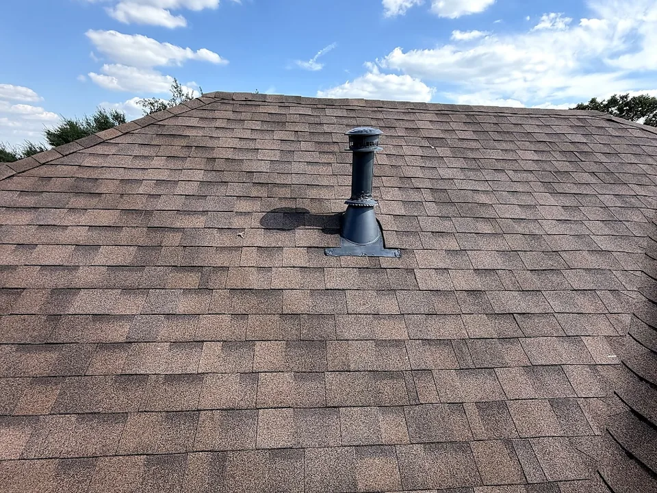 Pipe boot flashing around a plumbing vent on a brown architectural shingle slope