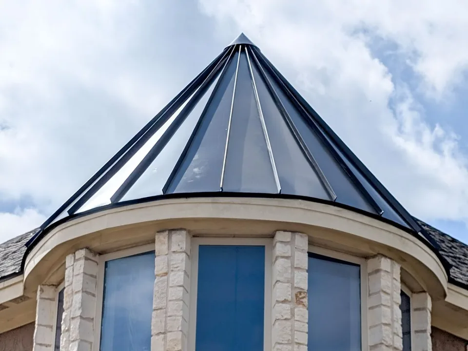 Dark standing seam metal roof on a round turret with stone columns
