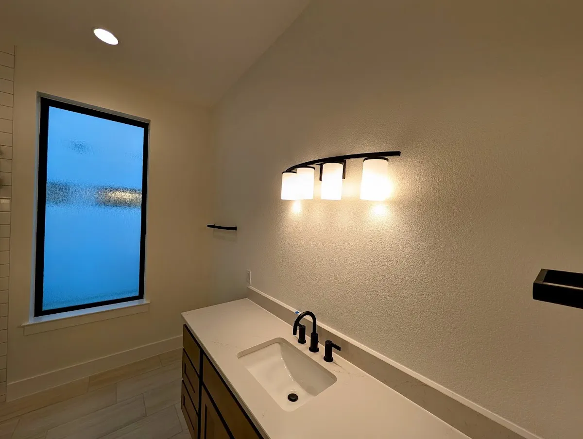 Bathroom wall finish after interior painting with light fixtures and clean surface texture.