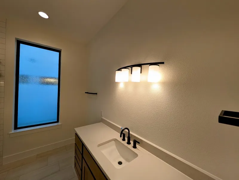 Bathroom wall finish after interior painting with light fixtures and clean surface texture.